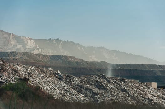 view of an open pit marble quarry showing heavy duty equipment and rock. High quality photo