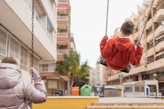 two children ride on a swing with their backs to the camera there is a place for an inscription. High quality photo