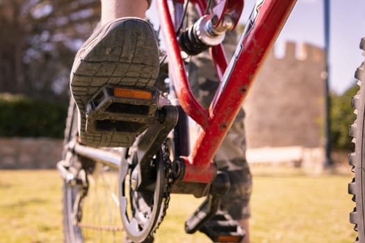 child's feet on the pedals of a bicycle close-up, the child is resting in the park, an active lifestyle of a teenager. High quality photo