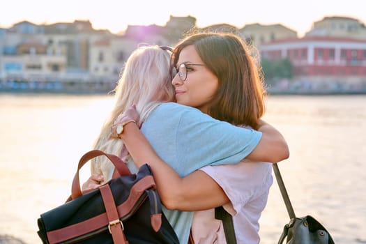 Portrait of mother and teenage daughter hugging happy. Family, girl and mom together on city's seaside summer embankment at sunset. Family, motherhood, mother's day, happiness, relationship, love
