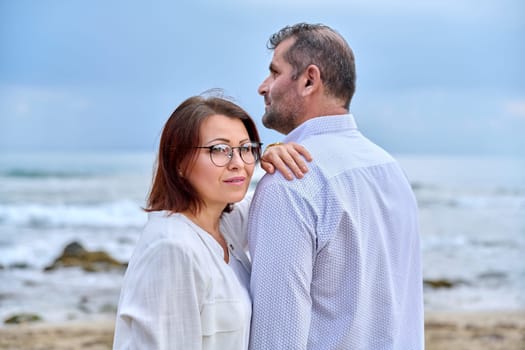 Outdoor portrait of mature couple embracing against the background of sea nature. Middle-aged happy romantic man and woman. Relationships, feelings, lifestyle, marriage, people concept