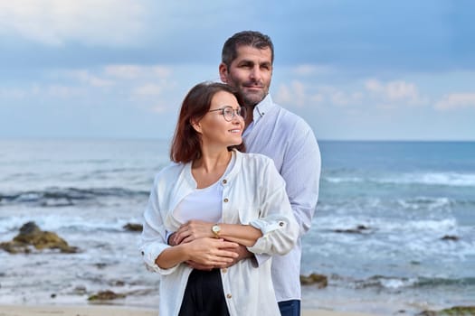 Outdoor portrait of mature couple embracing against the background of sea nature. Middle-aged happy romantic man and woman. Relationships, feelings, lifestyle, marriage, people concept