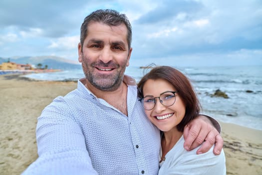 Happy mature couple taking selfie photo on smartphone. Middle-aged man and woman resting together at seaside resort. Relationships, feelings, lifestyle, marriage, people concept