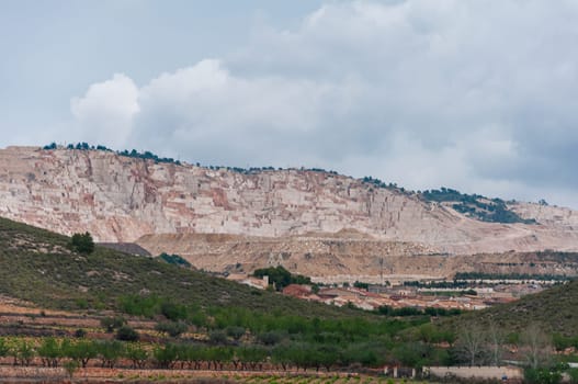 view of an open pit marble quarry showing heavy duty equipment and rock. High quality photo