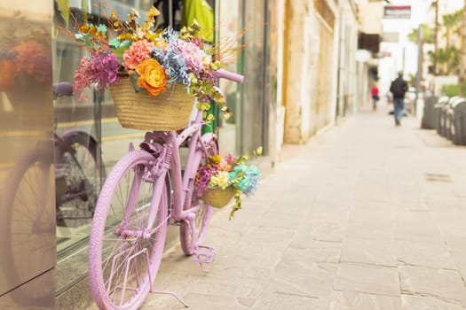 retor bicycle of pink color stands near the shop window decorated with flowers. High quality photo