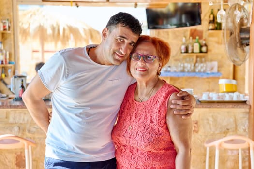 Portrait of happy middle aged son and elderly mom. Two generations of a family, a smiling man hugging his mother with love, looking at the camera. Family, motherhood, mothers day concept