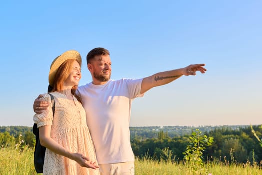 Happy middle age couple looking in distance at horizon, summer nature wild meadow background. Smiling man and woman together. People 40s, family, relationships, leisure, holidays, lifestyle concept