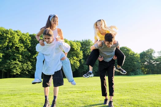 Teenage youth having fun in the park, happy laughing friends. Group of teenagers together on sunny day. Friendship, adolescence, summer, vacation, lifestyle, fun, happiness, holiday, leisure, people