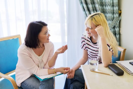 Woman teacher, therapist, social worker talking to teenage student in the office. Professional mental help of a psychologist. Education, counseling, therapy, adolescence concept