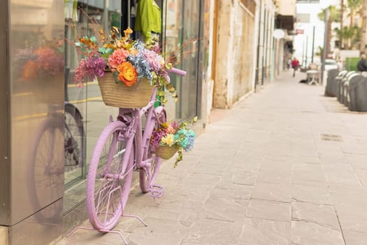 a shop window on the street, near the store there is a pink bicycle decorated with flowers, there is a place for an inscription. High quality photo