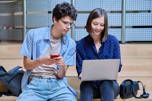 Friends classmates college students guy and girl with smartphone laptop inside educational building. Youth, lifestyle, technology, mobile applications for learning leisure communication