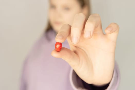 a teenager girl in a purple sweater holds a red vitamin in her hands close-up on a blurred background.Healthy lifestyle concept