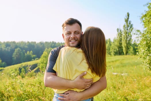 Portrait of happy adult hugging couple on summer sunny day. Beautiful people man and woman embracing in nature, male face close up, family, happiness, holidays, joy concept