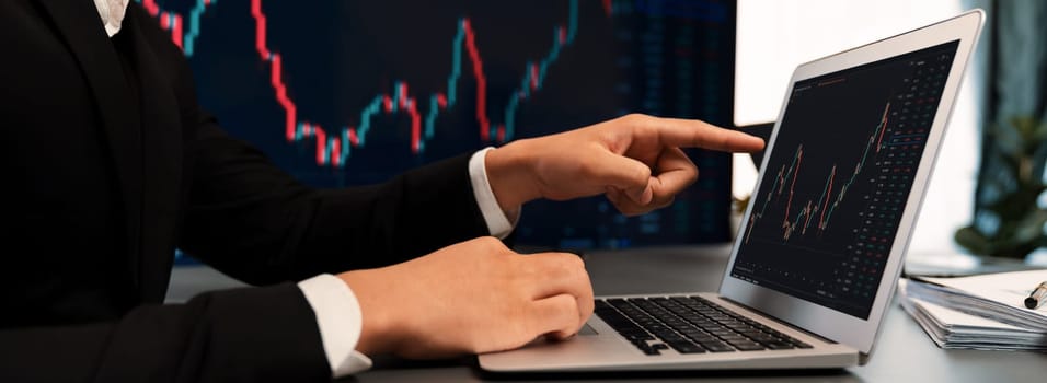 Stock trading investor finger pointing on dynamic financial data graph on monitor. Businessman or broker with analytic thinking analyzing data for stock market exchange trading company. Trailblazing