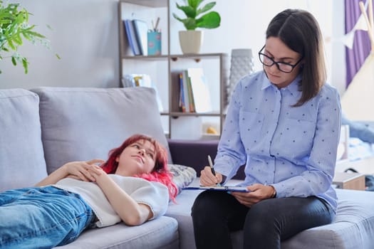 Psychologist helping teenage female, individual therapy in doctors office. Professional counselor listening teenager, girl lying on couch. Mental health, adolescence, psychology, psychiatry concept