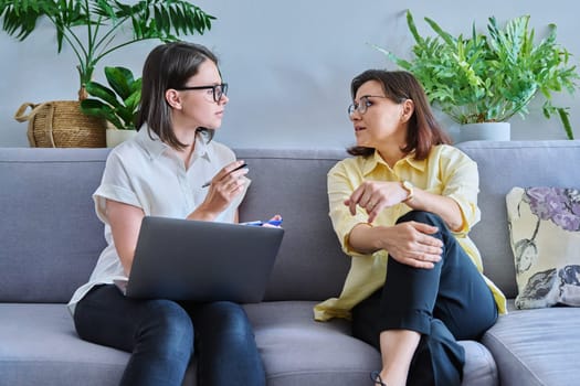 Middle aged woman in individual therapy, female psychologist and patient sitting together on couch in office. Psychology, counseling, psychotherapy, mental health, health care, mature people concept