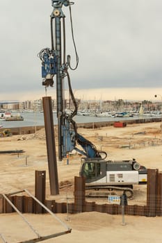 construction site near the pier with yachts, there are a lot of equipment at the construction site, various cranes and cars are standing. High quality photo