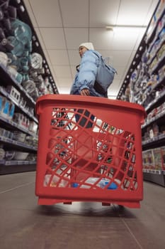 a girl of European appearance in a blue jacket and a white hat, standing in a store with a red cart, chooses dishes. High quality photo