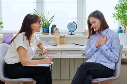 Sad stressed young woman in therapy with professional psychologist. Women talking in office, therapist counselor psychotherapist working with patient. Support, mental health, psychology, psychotherapy