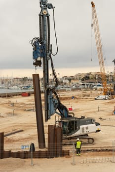 construction site near the pier with yachts, there are a lot of equipment at the construction site, various cranes and cars are standing. High quality photo