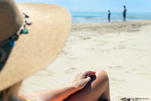 a girl in a hat, a close-up on the girl's tanned and slender legs, there is a place for an inscription, the photo from the back is made of a girl looking at a couple near the sea. High quality photo