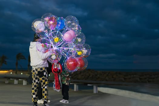 guy on the embankment sells beautiful balloons in the evening, a man stands with his back to the cameras and holds a lot of balloons in his hands there is a place for an inscription.High quality photo