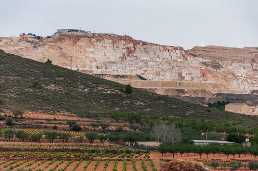 Landscape view of an open cast marble quarry showing heavy duty equipment and rock. High quality photo