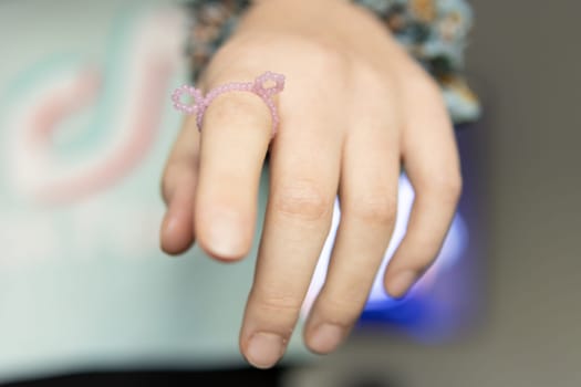 children's hand close-up on the finger a ring with pink beads on a blurred background.High quality photo