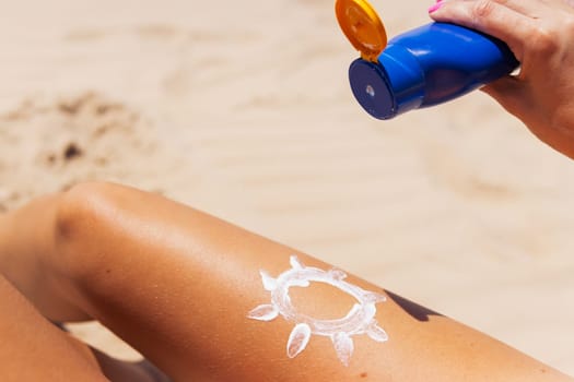 Close-up of a woman's hand applying sunscreen to her leg. skin care. Sun protection. A woman smears sunscreen with moisturizing lotion on her smooth tanned legs. High quality photo