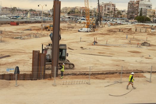 Construction site of public buildings on hills near sea coastline. Cranes during lifting operations. High quality photo