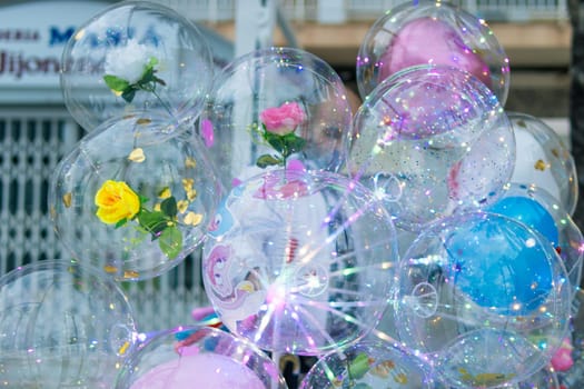 a lot of multi-colored Balloons close-up on the street, a lot of balls inside them are roses and multi-colored sparkles. there is a place for an inscription. High quality photo