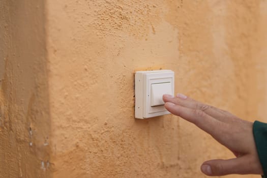 Female hand presses the doorbell button on the street close-up .there is a place for the inscription. High quality photo