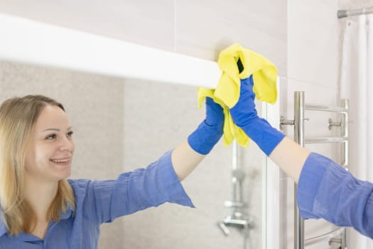 girl washes the mirror in the bathroom cleaning concept. High quality photo