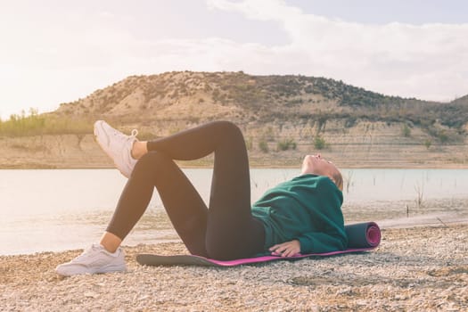 successful female hiker enjoys mountain peak view meditating lying on yoga mat ,beautiful nature landscape with woman. High quality photo