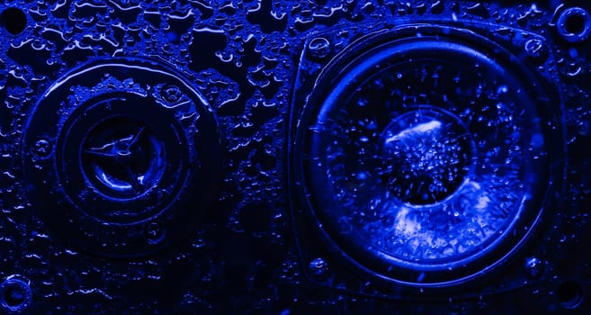 Abstract concept of powerful sound speakers in blue neon light with water drops. High quality photo