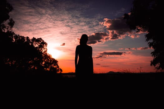 silhouette of a sports girl in a dress at sunset in nature the girl looks at the sunset, there is a place for an inscription. The concept of freedom. High quality photo