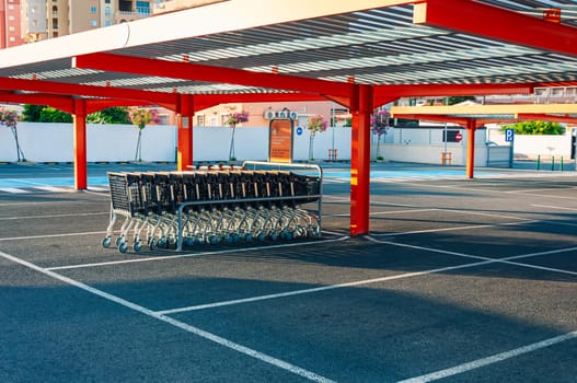 Many rows of orange trolleys outside the store with a close-up of the parking lot, there is a place for an inscription. Spain, Torrevieja shop Consum , August 10, 2023 High quality photo