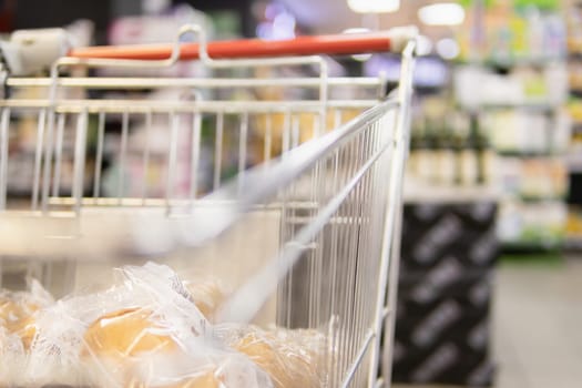 grocery cart rides through the supermarket The grocery cart is rolling through the supermarket, focus on the cart.