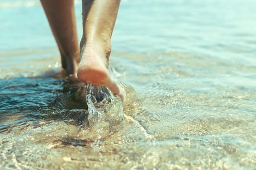 Vacation concept. Close up of female legs walking by the beach. High quality photo