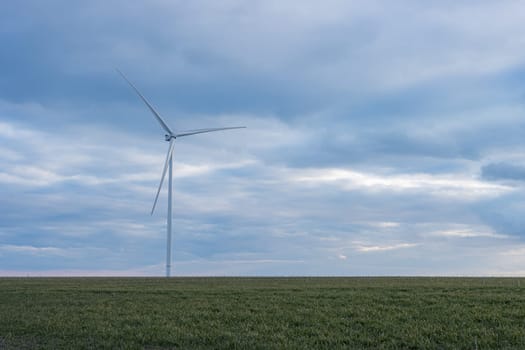 View from the car to a rural road with a field and windmills. View of the green field and fields after the harvest. High quality photo