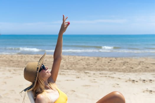 Beautiful seascape with a girl, a slender girl in a hat and swimsuit relaxes and lies on a sun lounger on the beach alone happy, there is a place for an inscription. High quality photo