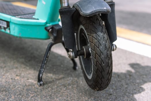 front wheel from an electric scooter close-up, the scooter stands on a leg on the street. High quality photo