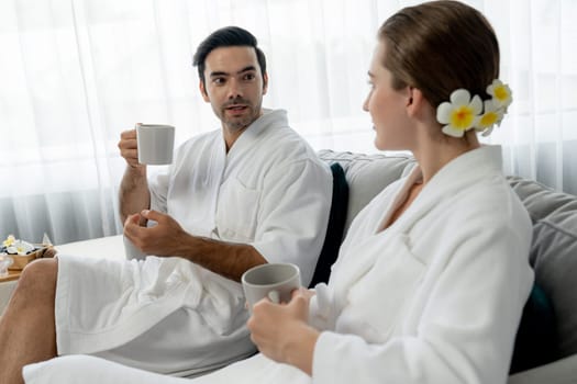 Beauty or body treatment spa salon vacation lifestyle concept with couple wearing bathrobe relaxing with drinks in luxurious hotel spa or resort room. Vacation and leisure relaxation. Quiescent