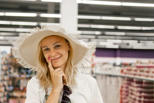 portrait of a smiling girl in a store,girl trying on a sun hat in a store.shopping concept. High quality photo