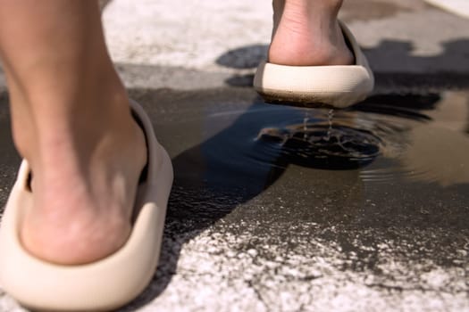 close-up on the legs in brown slippers, female legs cross the puddle on the street close-up on the legs and the puddle. High quality photo