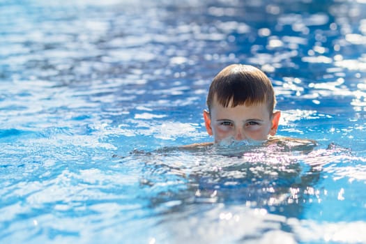 Happy boy swims and dives underwater. Active healthy lifestyle, water sports and activities with parents on summer family vacation with child. High quality photo