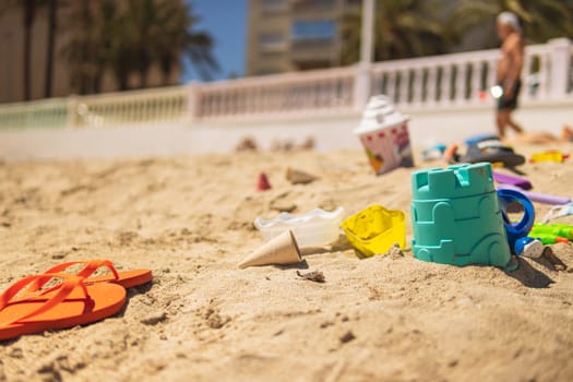 Bright plastic children's toys in the sand. The concept of a beach holiday for children. view from above. Place for text. Flat lay, top view, copy space. High quality photo