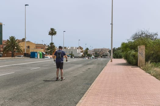 a man rollerblading down the road with his back to the camera. High quality photo