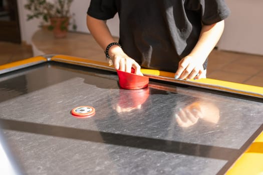 Hands of young people holding striker on air hockey table. Friends playing air hockey. High quality photo