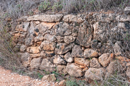 a stone fence made by a man in a field close-up, there is a place for an inscription. dry grass around. High quality photo